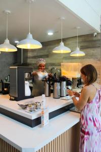 a woman standing in a kitchen looking at her cell phone at Hotel Genova Prado in Barranquilla +38 photos