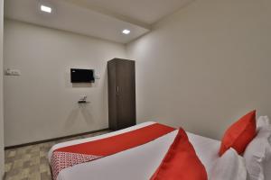 a bedroom with a bed with red pillows and a tv at Hotel O Ripple Mall in Surat +28 photos