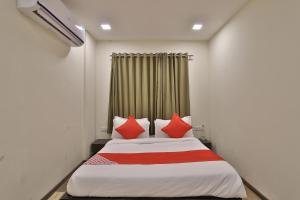 a bedroom with a bed with red pillows at Hotel O Ripple Mall in Surat