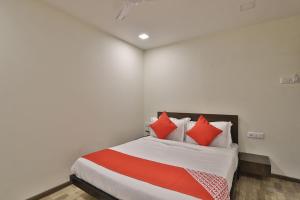 a bedroom with a bed with red pillows on it at Hotel O Ripple Mall in Surat