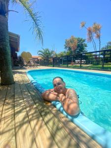 Ein Mann, der auf einem Floß im Schwimmbad liegt. in der Unterkunft Pousada Coração do Rosa in Praia do Rosa