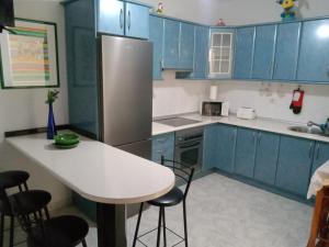 a kitchen with blue cabinets and a white table and chairs at Casa Klemann with private sun terrace in Cruce de Arinaga