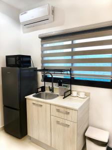 La cuisine est équipée d'un évier et d'un réfrigérateur noir. dans l'établissement Appartement Palms Abidjan, à Abidjan