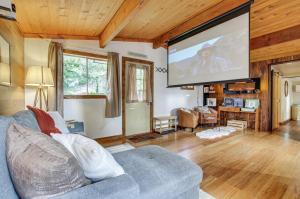 a living room with a couch and a large screen at Arlington Creekside Cabin with Hot Tub and Fire Pit! in Arlington