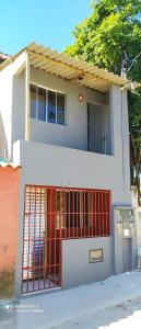 a white house with a red gate in front of it at Mini Casa em Arraial d'Ajuda in Porto Seguro