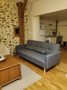 a couch in a living room with a stone wall at Le Relais d'Anglards in Anglards-de-Saint-Flour