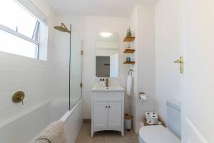a bathroom with a tub and a sink and a mirror at Greenpoint Emerald in Cape Town +32 photos