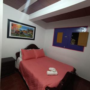 a bedroom with a red bed with two towels on it at Hostal Palmas De Cocora in Salento