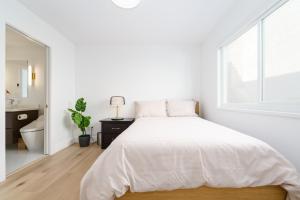 a white bedroom with a large bed and a window at Steveston Village Bed and Breakfast in Richmond