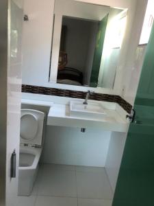 a bathroom with a sink and a toilet and a mirror at Suíte com janela para o jardim in Goiânia