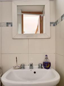 un lavandino bianco in un bagno con specchio di Bright brand new studio a Olivos
