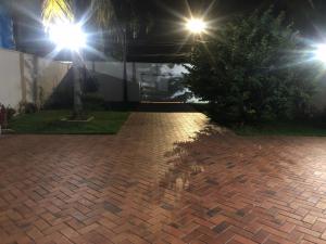 a brick driveway at night with street lights at Suíte com janela para o jardim in Goiânia