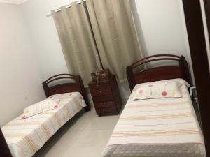 two twin beds in a room with a dresser at Suíte com janela para o jardim in Goiânia