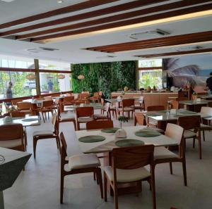 Flat com vista para piscina principal في إيبوجوكا: غرفة طعام مع طاولات وكراسي في مطعم