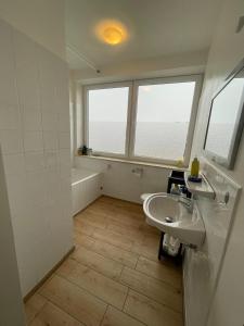 a bathroom with a sink and two windows and a tub at Zimmer Vermietung in Pattensen