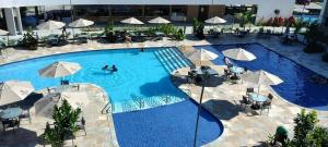 Flat com vista para piscina principal في إيبوجوكا: مسبح كبير فيه مظلات والناس فيه