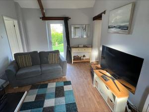 a living room with a couch and a flat screen tv at Beech Cottage in Ilfracombe
