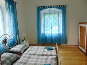 1 dormitorio con 1 cama y una ventana con cortinas azules en Pension Poledník, en Weissbach
