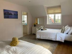 a bedroom with two beds and two windows at Langford farmhouse - Luxury 4bd, hot tub, cinema, 10 acres in Bartley
