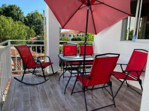 - une table et des chaises avec un parasol rouge sur la terrasse couverte dans l'établissement Vasquez apartamentos, à La Piña