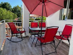 a table and chairs with a red umbrella on a porch at Vasquez apartamentos in La Piña
