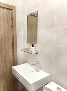 a white bathroom with a sink and a mirror at Appartement Palms Abidjan in Abidjan
