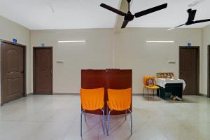 two orange chairs in a room with a table at Collection O Senthamizh Residency in Chennai