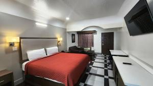 Una habitación de hotel con una cama roja y un sofá. en Scottish Inn & Suites Sam Houston Parkway, en Houston