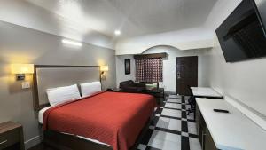 ヒューストンにあるScottish Inn & Suites Sam Houston Parkwayの赤いベッドとソファが備わるホテルルームです。