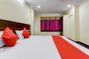 a bedroom with a large white bed with red pillows at Collection O Hotel Srinivasa Residency in Tirupati