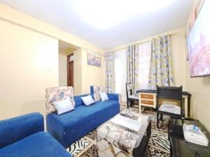 a living room with a blue couch and a desk at IMMARA BNB in Nakuru