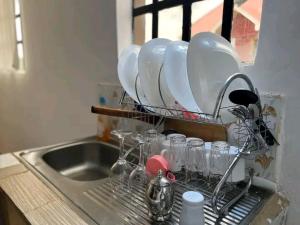 a drying rack with glasses and plates on a kitchen sink at IMMARA BNB in Nakuru