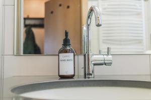a bottle of soap sitting on a bathroom sink at ALPSTAY Eulennest - Ski-In & Ski-Out in Bad Kleinkirchheim +23 photos