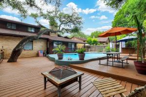 a deck with a pool and a table and an umbrella at Rakuen - A Birdy Vacation Rental in San Antonio