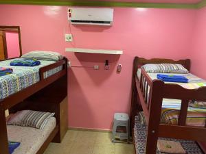 Habitación con 2 literas y pared de color rosa. en Apart Hotel - Alter Temporada, en Manaus
