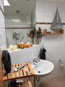 ein Badezimmer mit einem Waschbecken, einem Spiegel und einem weißen Waschbecken in der Unterkunft Ferienwohnung Bernsteinwind in Graal-Müritz