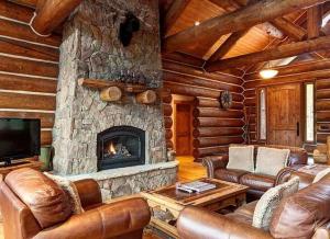a living room with leather furniture and a stone fireplace at Big Timber Lodge by Ski Country Resorts in Breckenridge