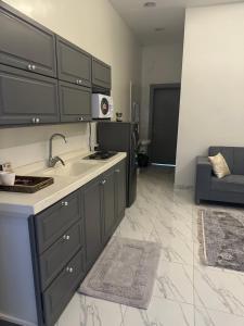 a kitchen with gray cabinets and a sink and a couch at شقة فاخرة للايجار اليومي in Al Kharj