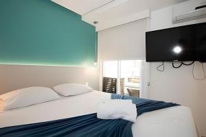 a bedroom with a bed with a flat screen tv on the wall at Hotel Brisas do Lago Brasília - Ozped Flats in Brasilia