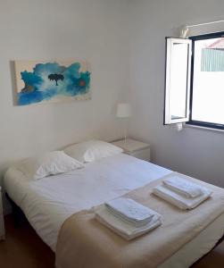 a bedroom with a white bed with towels on it at Inncork Guesthouse in Ponte de Sor