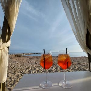 two wine glasses sitting on a table on the beach at Matchpoint Apartment in Sanremo
