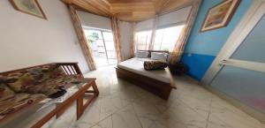 a bedroom with a bed and a couch and windows at Hôtel Restaurant Gites Kribi in Kribi