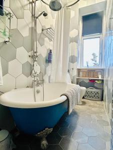 baño con bañera azul y blanca y ventana en Glasgow Center/West End Apartment, en Glasgow
