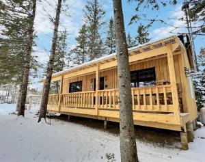 uma casa de madeira na floresta na neve em Ranch de Frisons le Fer à Cheval - Le Madison - Chalet Rustchic au pied du Mont Mégantic em La Patrie