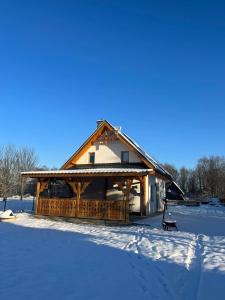 a log cabin in the snow with snow covered ground at Apartament Janusza in Gronków