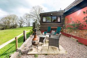 a patio with chairs and a table and a house at The Retreat in Llanrhaeadr-ym-Mochnant