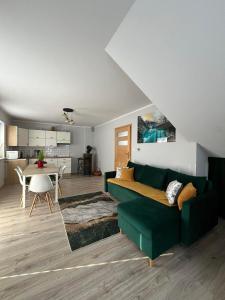 a living room with a green couch and a kitchen at Apartament Janusza in Gronków