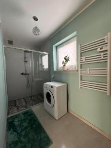 a bathroom with a washing machine and a shower at Apartament Janusza in Gronków