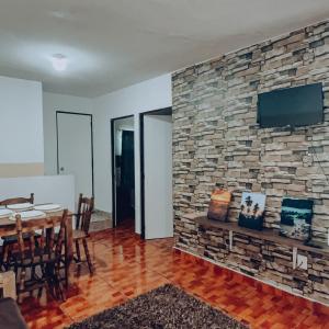 ein Esszimmer mit einer Steinmauer und einem TV in der Unterkunft Bonito departamento y centrico in Lázaro Cárdenas