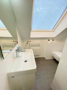 uma casa de banho com um lavatório branco e uma clarabóia em Cute Apartment - Detmold city center - large kitchen, bath, south facing balcony - free parking and wifi em Detmold